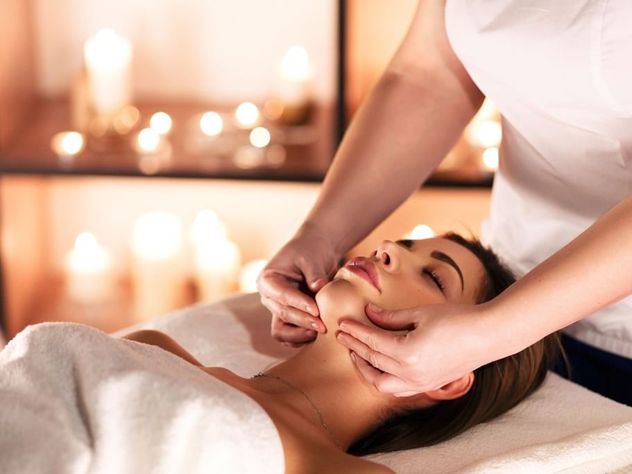 Woman receiving a relaxing facial massage by a professional in a spa setting.