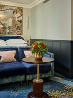 Deluxe King Bedroom with blue armchairs by a flower-topped table at The Capital Hotel, Apartments & Townhouse