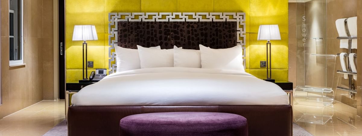 Amarillo Suite featuring a bed with a striking yellow headboard and ottoman at The May Fair Hotel