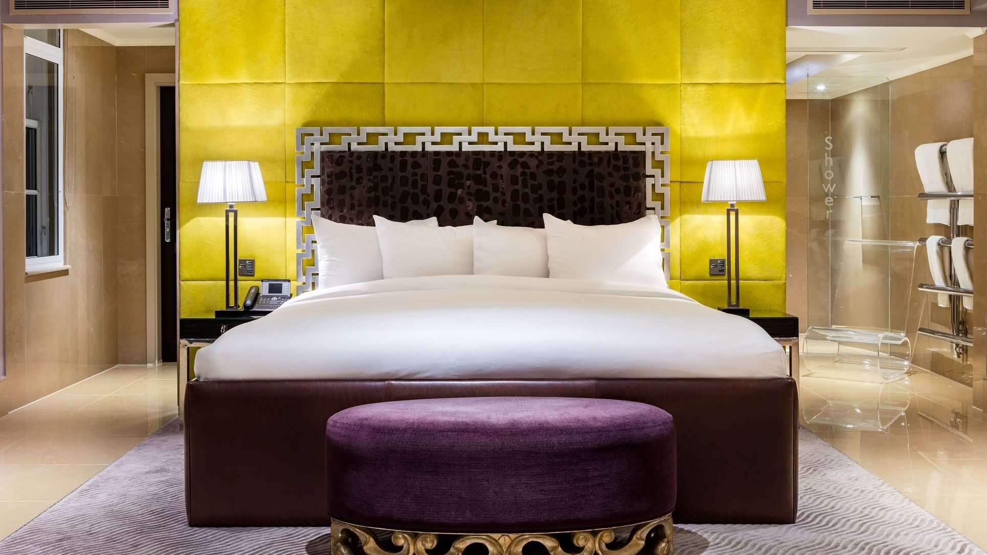 Amarillo Suite featuring a bed with a striking yellow headboard and ottoman at The May Fair Hotel