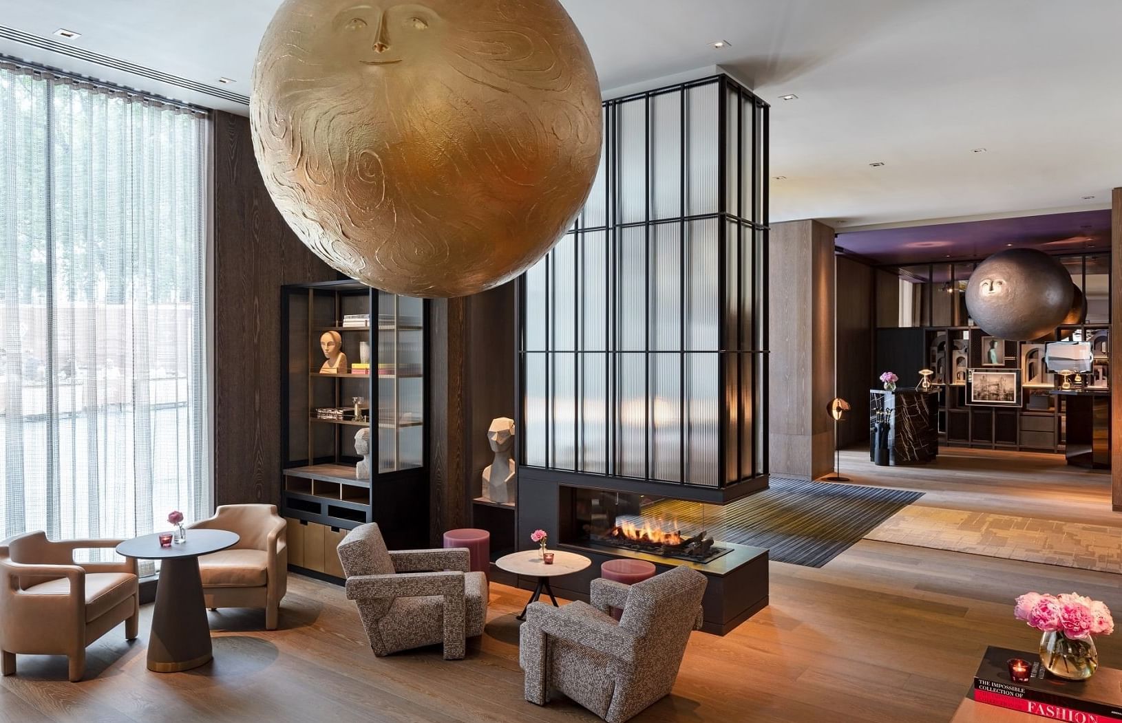 Elegant lobby interior at The Londoner, with a unique sculpture, modern fireplace, and comfortable seating