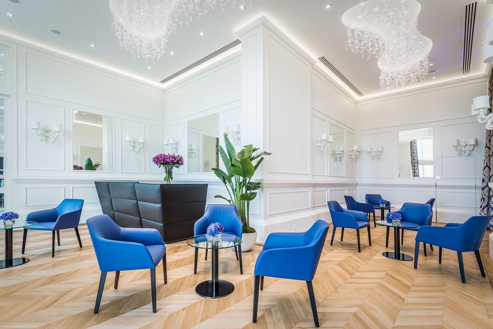 Front desk area with chairs, herringbone floor, and modern chandeliers at Polonia Palace Hotel