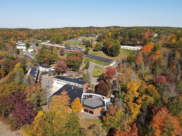 {Aerial view of a colorful autumn landscape featuring a lake and vibrant trees near Cove Pocono Resorts}