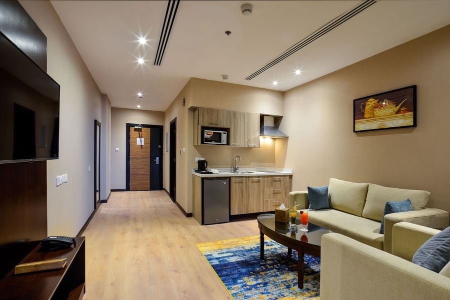 Living area with sofa and a kitchenette in Junior Suite at Naviti By Warwick Dammam