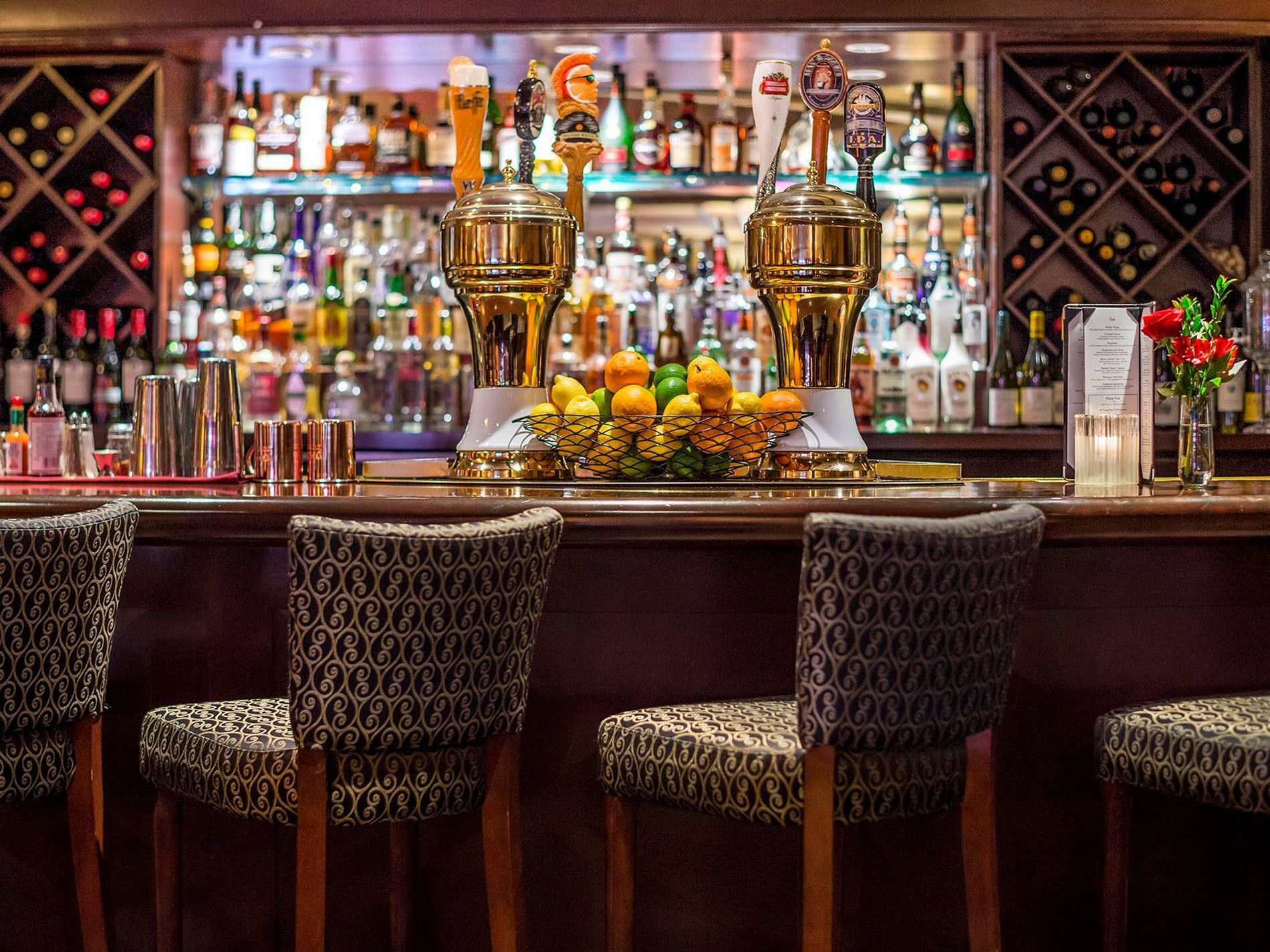 Hotel bar featuring beer taps and a basket of citrus by patterned bar stools at Warwick Seattle