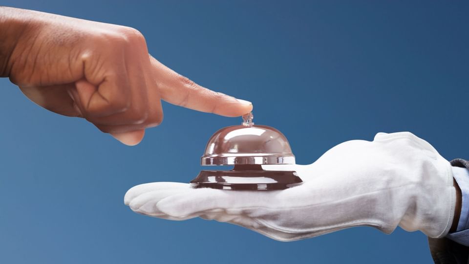 Primer plano de una mano presionando el timbre de servicio, destacando el servicio de mayordomo en Las Casitas Village.