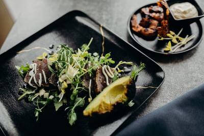 Tuna steak appetizer with a side of avocado, sprouts, and a creamy drizzle at The Boulevard Inn & Bistro