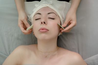 Guest receiving a relaxing facial treatment with gua sha stones on her cheeks at La Tourelle Hotel and Spa