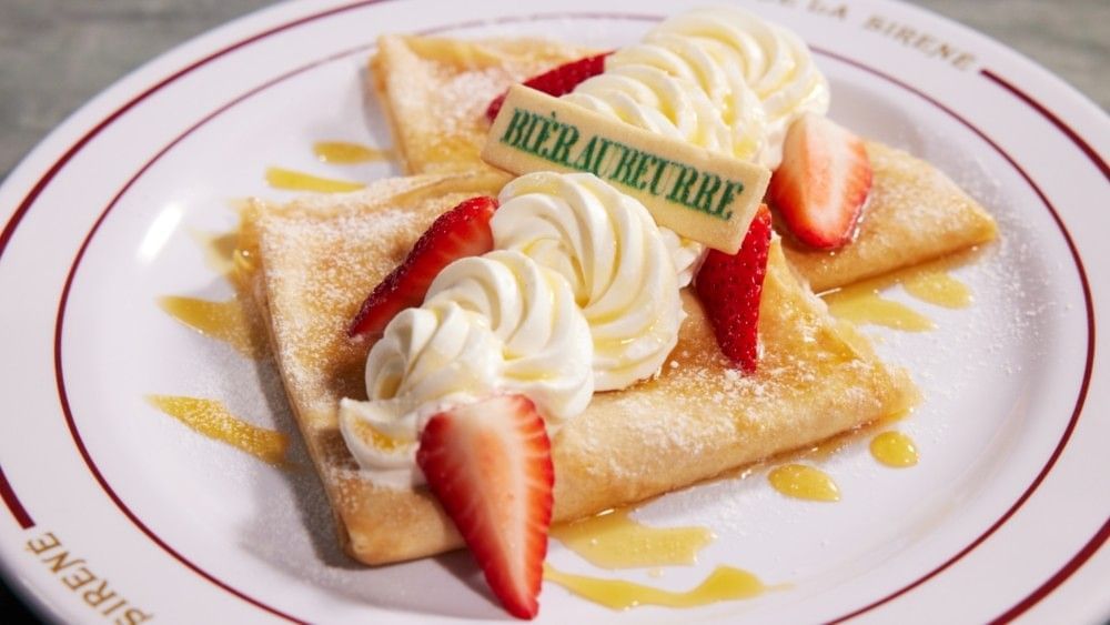 A close-up of a plate of crepes topped with strawberries and whipped cream from Cafe L'air la Sirene at Epic Universe.