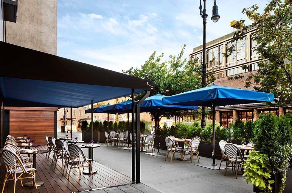 Outdoor dining with chairs, tables and umbrella in C+C at Gansevoort Meatpacking NYC