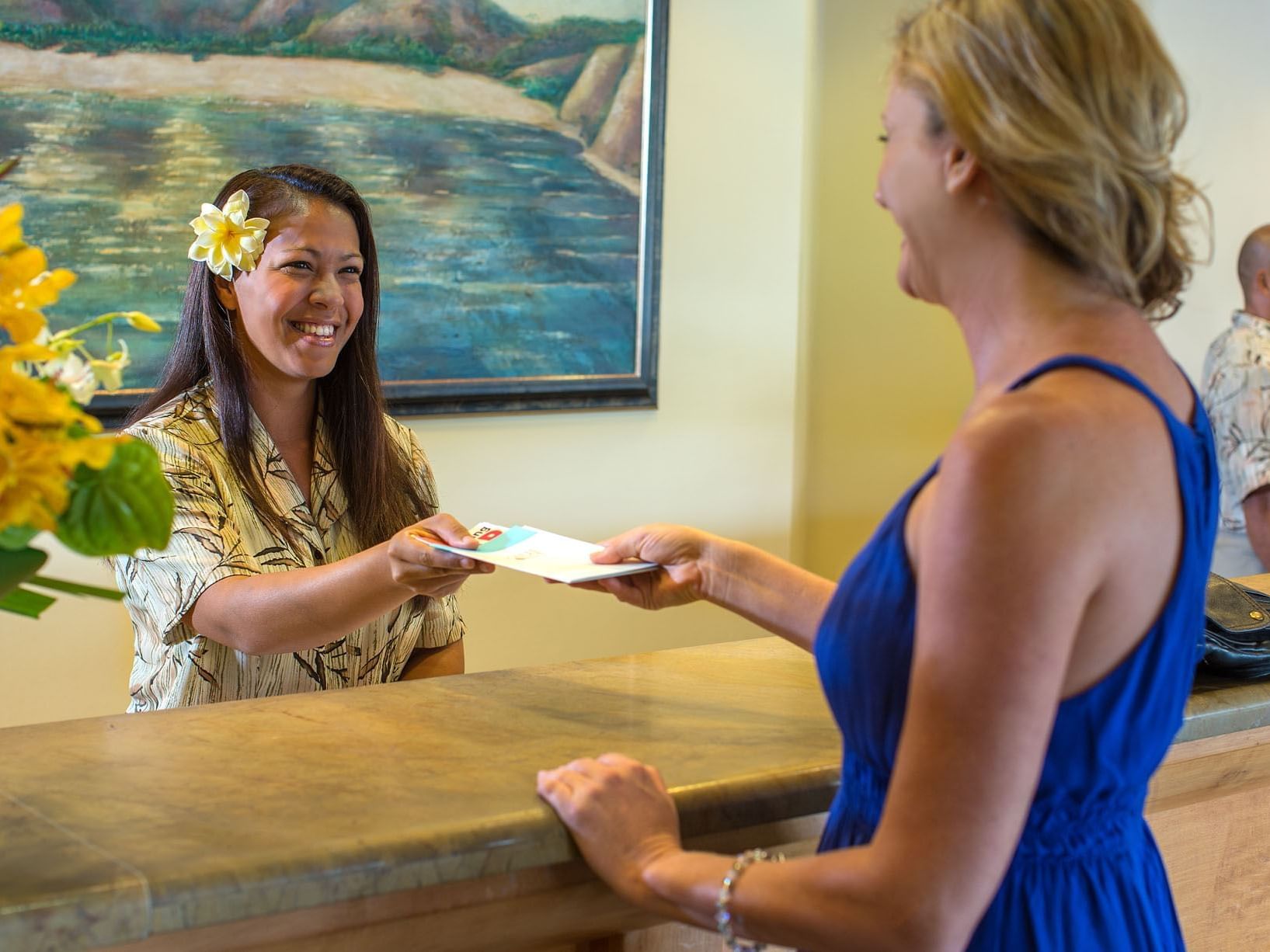 Receptionist & guest greeting with smiles at Maui Coast Hotel