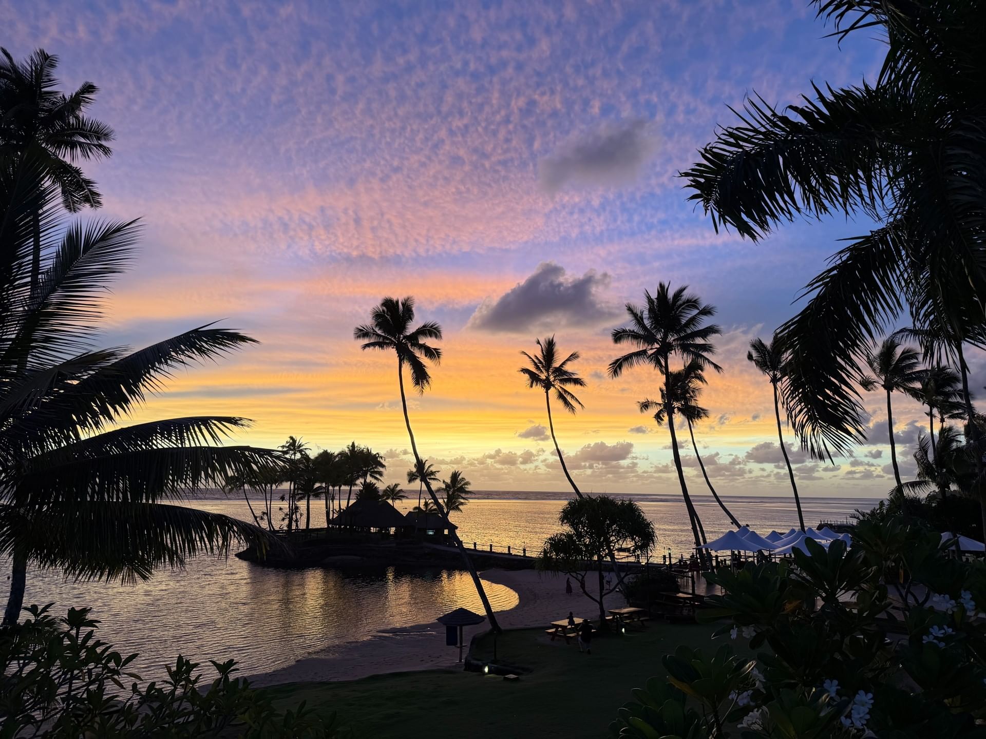 Sunset over tropical beach with coconut trees and ocean view at Warwick Fiji Resort and Spa.