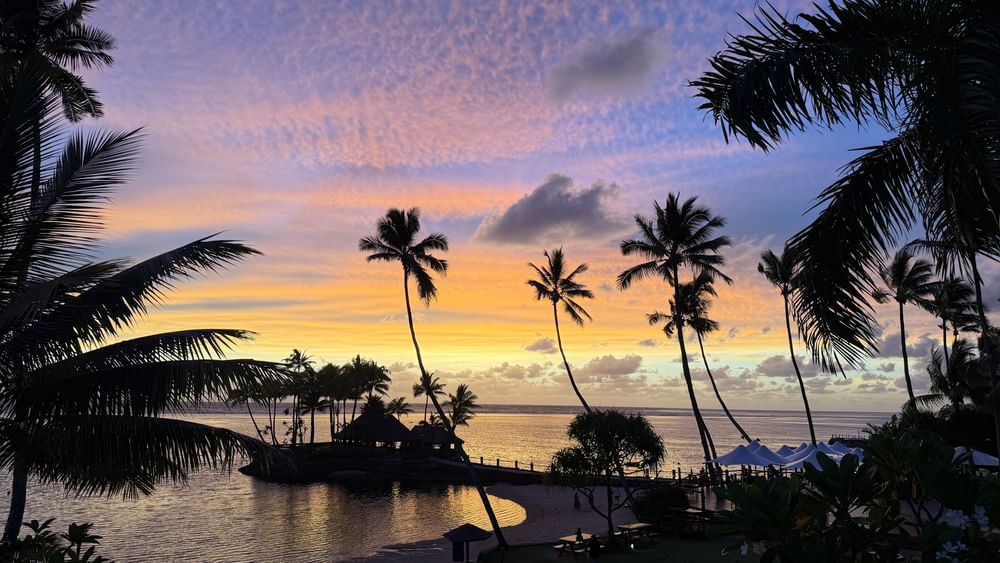 Sunset view over ocean and beach with palm trees at Warwick Fiji Resort and Spa in Korolevu.