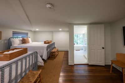 Classic Two Queen room with cozy beds, wooden floors, and adjoining bathroom at The Ashbrook Hotel