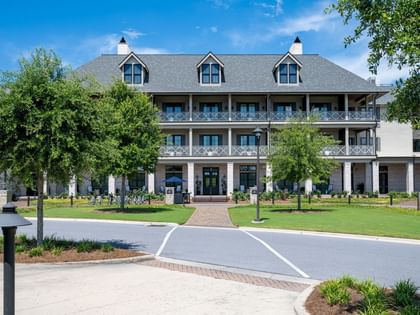 Wide paved driveway leading to a three-story building with white columns and balconies at Camp Creek Inn in Inlet Beach.