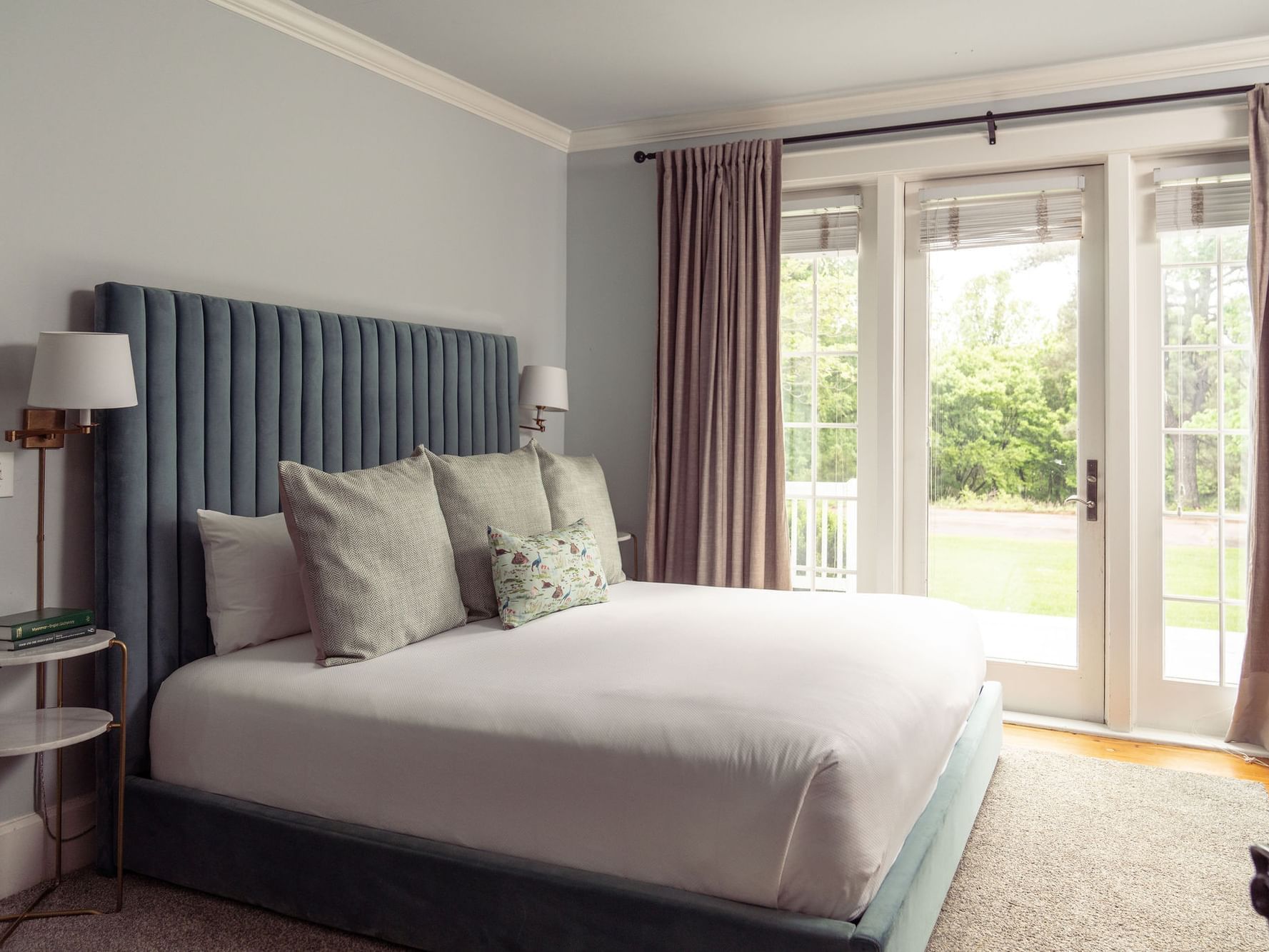 Elegant bedroom with blue headboard and French doors at The Clifton, Charlottesville.