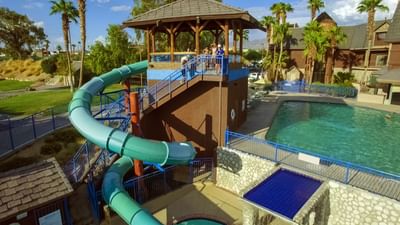 Outdoor water park with green spiral slide, gazebo tower, and multi-level pools at London Bridge Resort