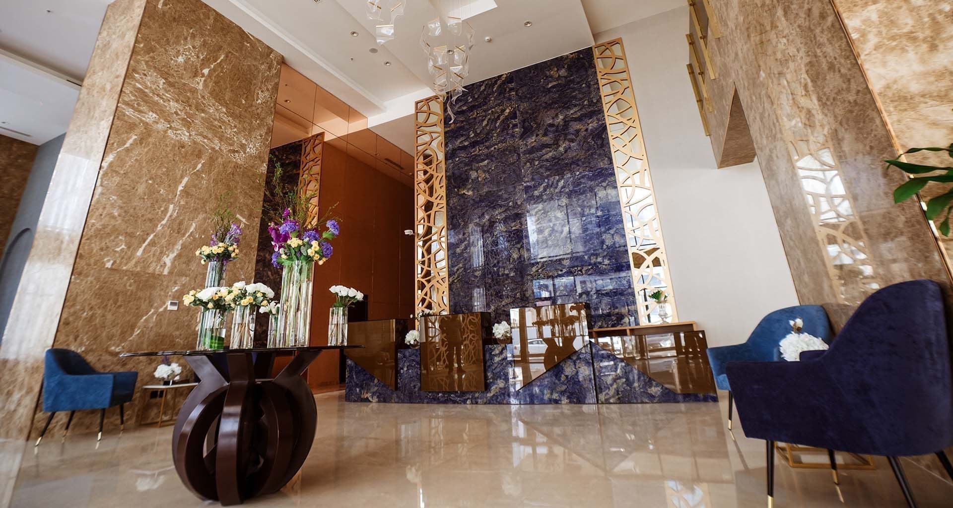 Low-angle view of the lobby area with Blue velvet chairs by a flower table at Cantonal Hotel by Warwick Riyadh