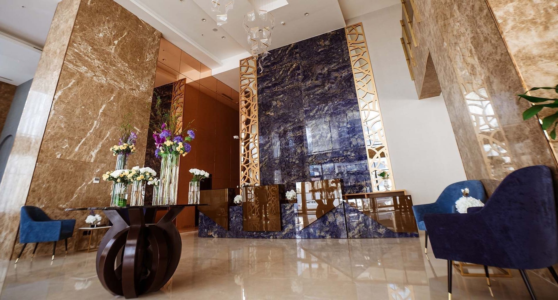 Low-angle view of the lobby area with Blue velvet chairs by a flower table at Cantonal Hotel by Warwick Riyadh