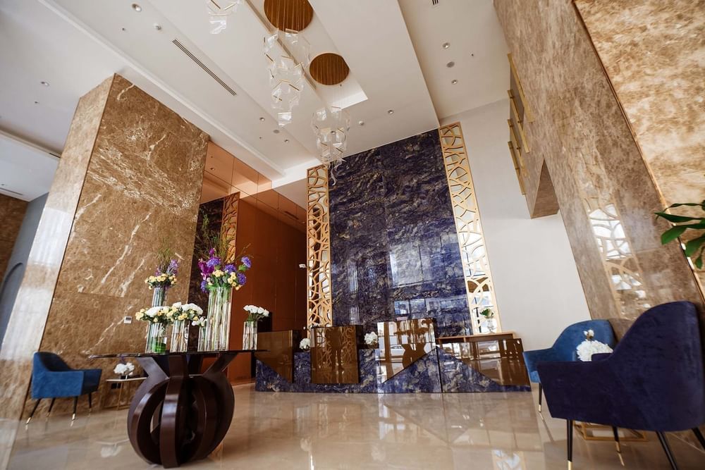 Low-angle view of the lobby area with Blue velvet chairs by a flower table at Cantonal Hotel by Warwick Riyadh