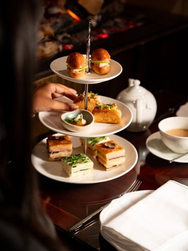 Présentoir à trois étages garni de sandwichs, pâtisseries et brioches avec théière et tasse à l'Hôtel Westminster Paris.