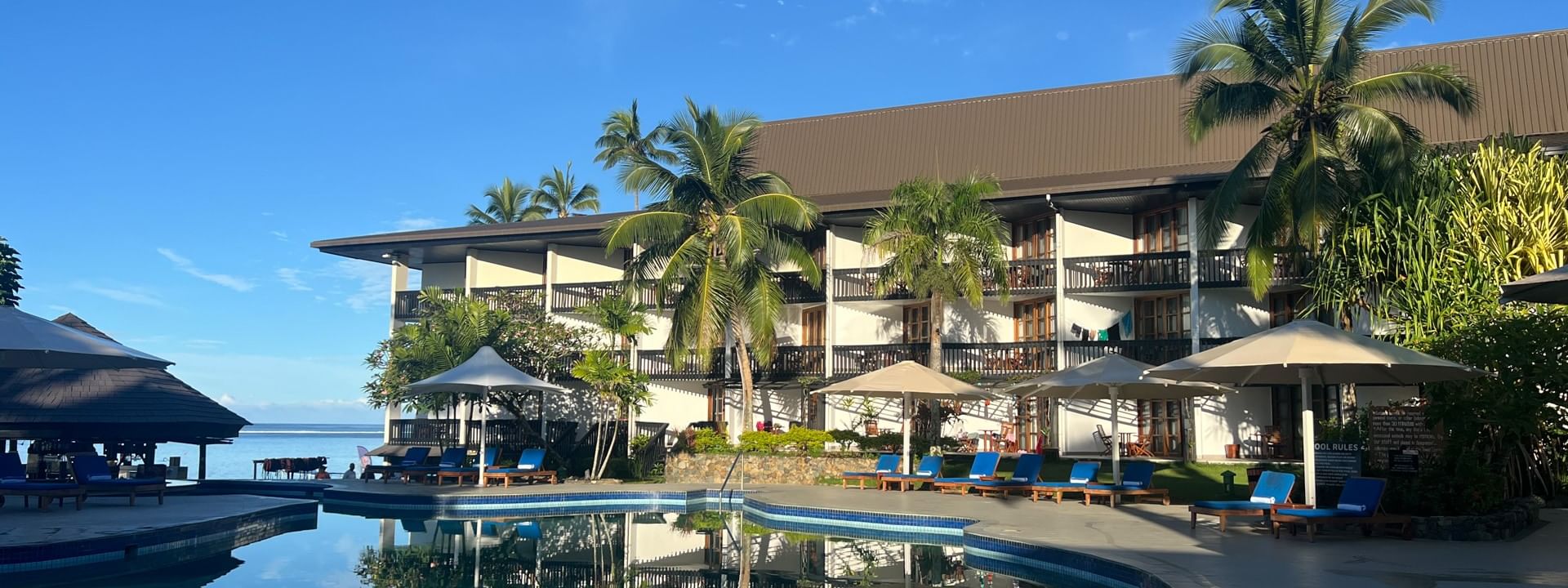 Swimming pool with blue lounge chairs under umbrellas at Warwick Fiji Resort and Spa in Korolevu