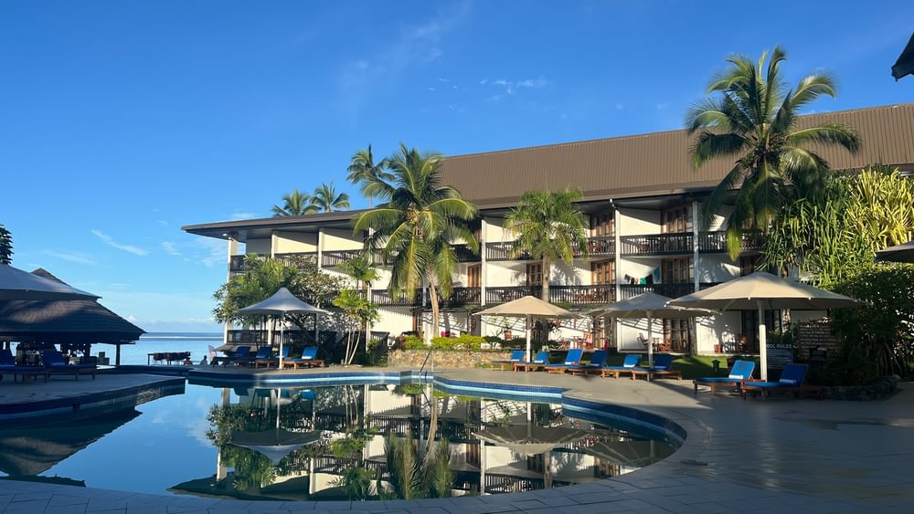 Swimming pool with blue lounge chairs under umbrellas at Warwick Fiji Resort and Spa in Korolevu.
