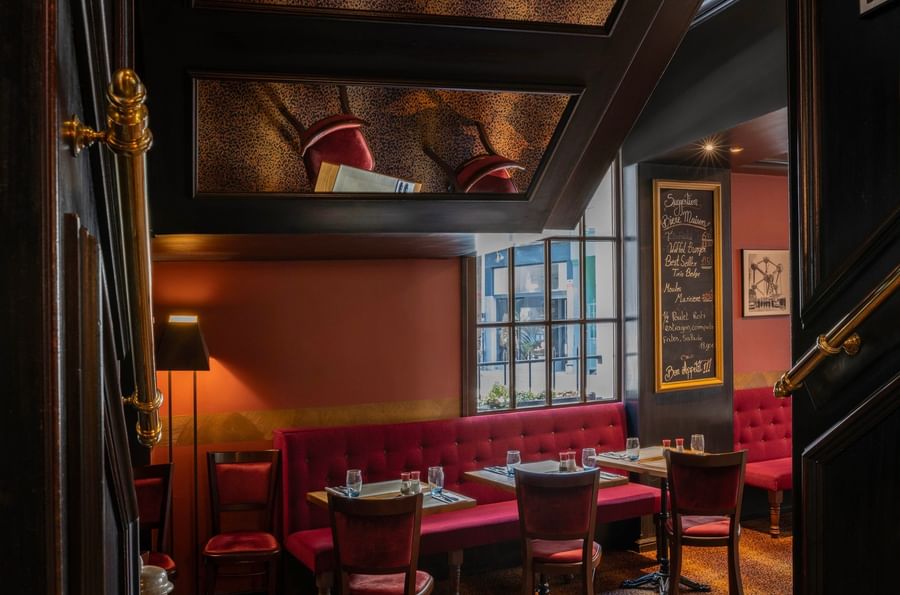 Dining tables & comfortable banquette seating near a window under a distinctive ceiling feature at The Chutney\’s Restaurant
