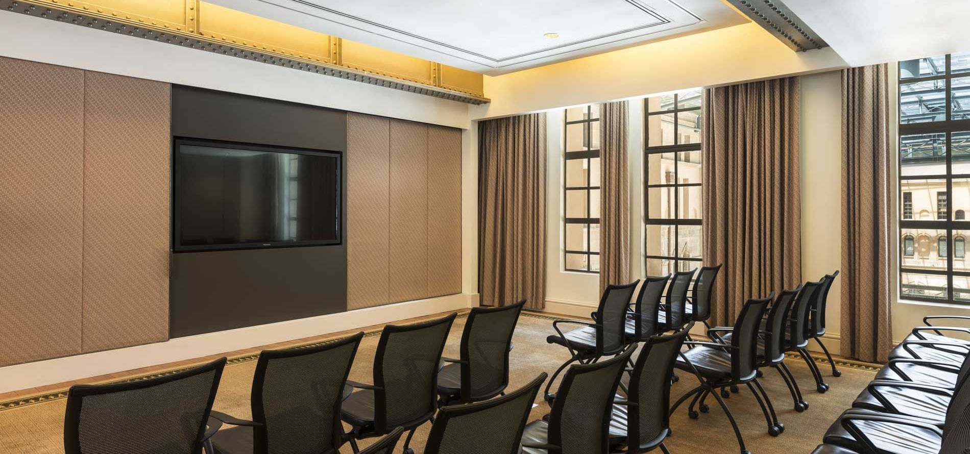 Rows of chairs face a TV in meeting room at The Fullerton Hotel Sydney