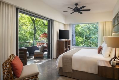 Comfy bed with large windows and a hanging chair on the balcony in Habitat Superior at El Mangroove Hotel