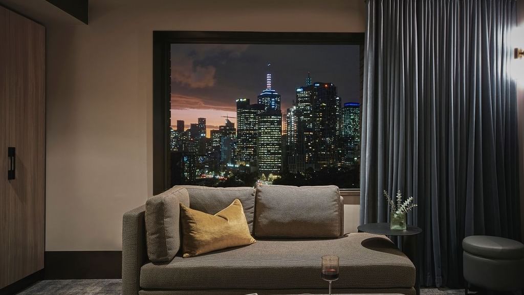Superior Suite lounge area with city skyline view at dusk at Pullman East Melbourne