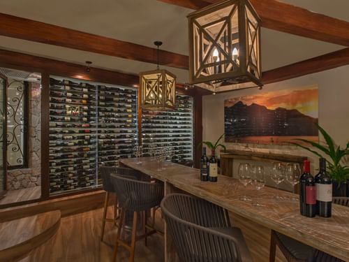 Bodega De Cortez con bar, lámparas rústicas y una pared de botellas de vino en Hacienda del Mar Los Cabos