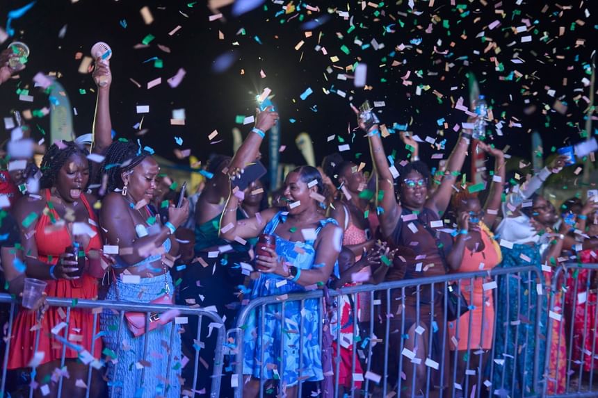 Crowd celebrates at Taste The Bay 2025 festival, arms raised at night near Bay Gardens Hotels and Resorts