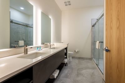 Bathroom interior with vanity, shower area, and light gray tile flooring in Dunedin hotel rooms at The J Hotel