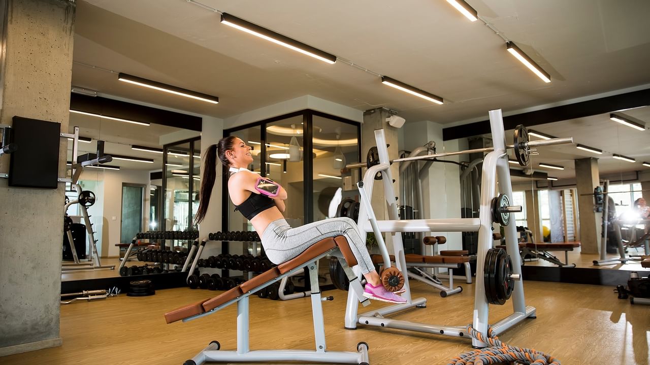 Woman doing leg exercises on a decline bench in a gym with other equipment visible.