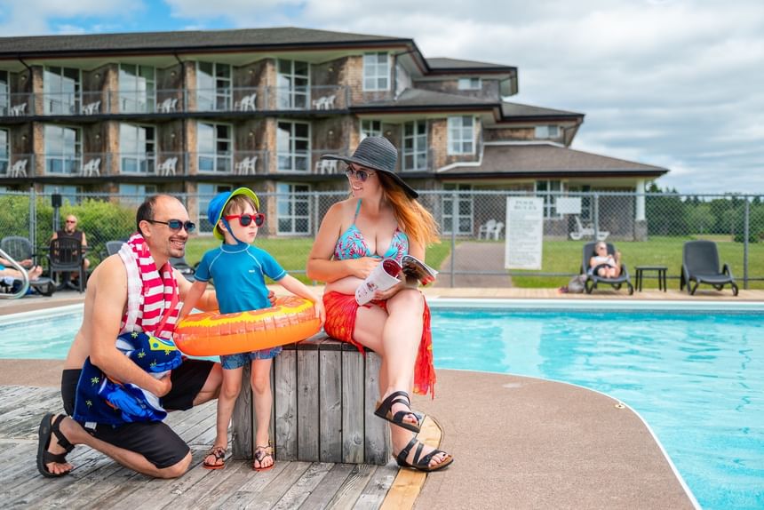 Family sitting by an outdoor pool under a cloudy sky at Rodd Brudenell River Resort, featuring the best accommodations in PEI