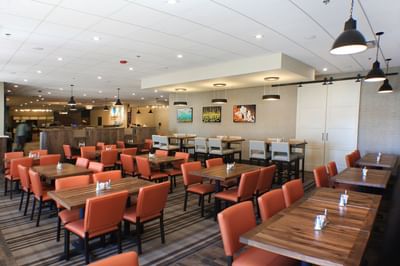Modern dining area with orange chairs and a large tables equipped at QT's Restaurant in Buffalo Bill Village