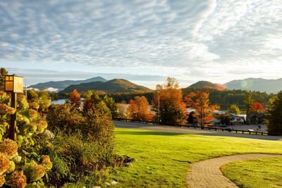 Autumn view from the Lake Placid Club Grandview showing a brick path, a grassy lawn and colorful trees against mountains