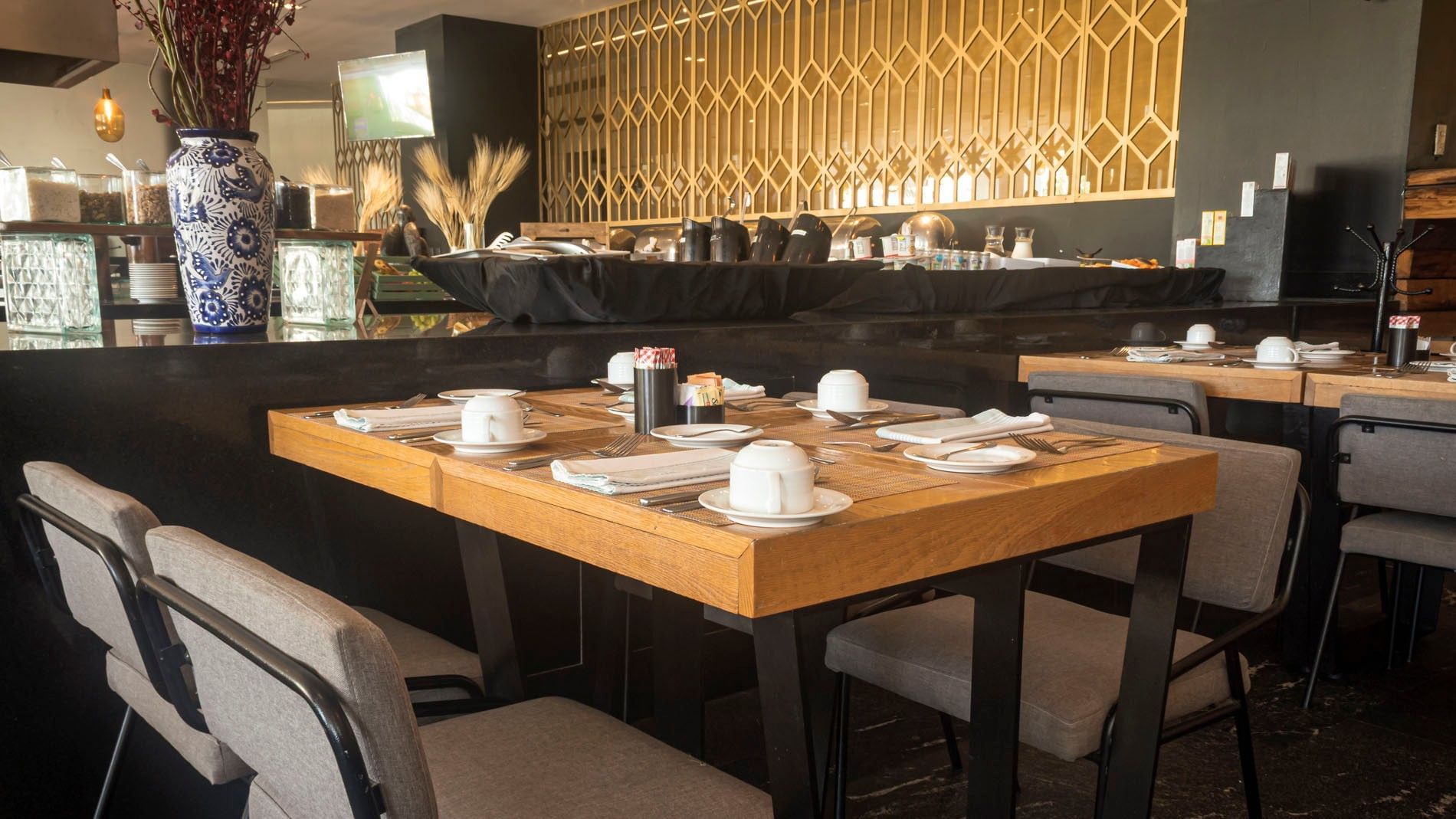 La Huerta restaurant showing set wooden tables and a gold room divider at Camino Real Puebla Angelopolis