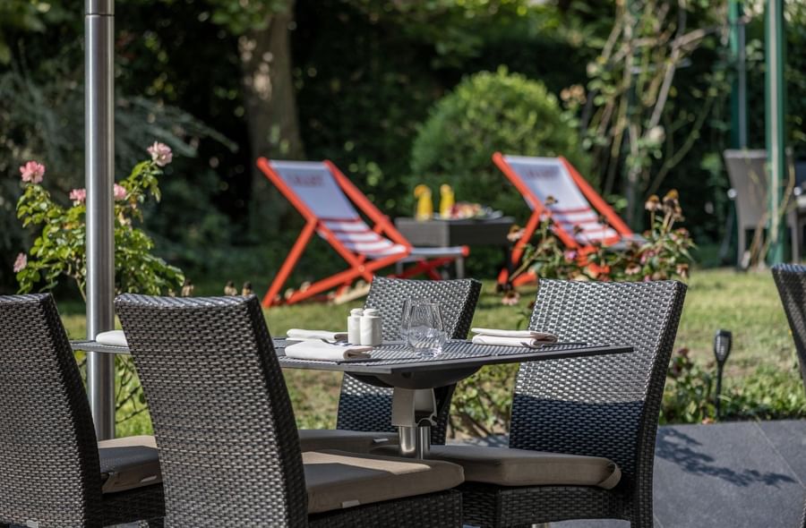 Outdoor patio set with woven chairs and a table set for dining at The Lounge Bar & Terrace in Warwick Reine Astrid - Lyon