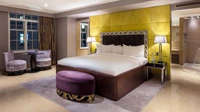 The Amarillo Suite at The May Fair Hotel, London, featuring a large bed with striped chairs and soft lighting