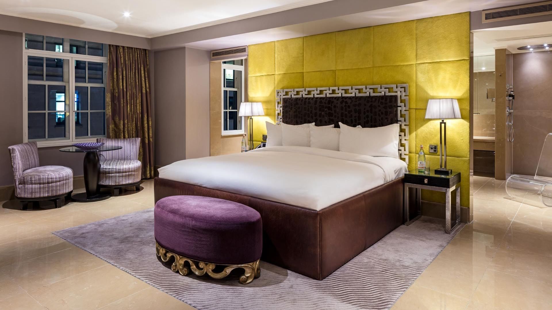 Luxurious Amarillo Suite at The May Fair Hotel London featuring a large bed with striped chairs, and soft lighting