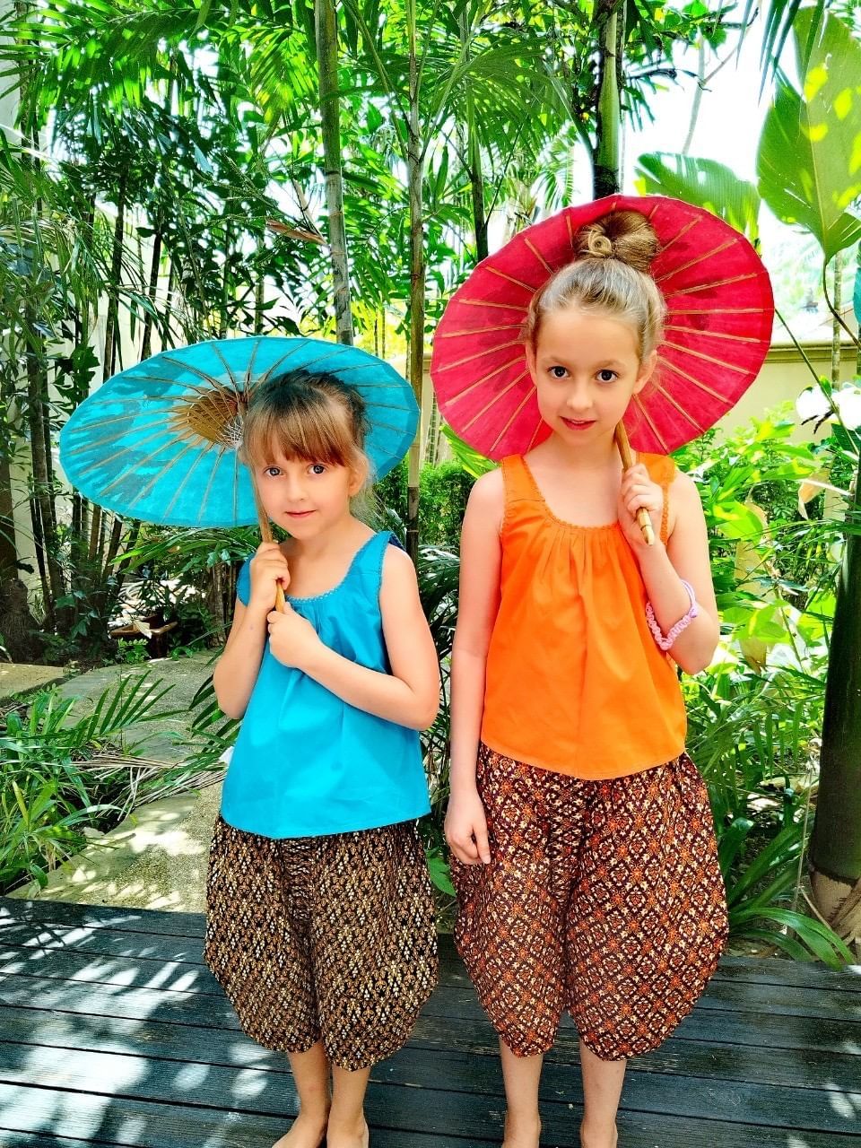 Two kids, wearing a Thai traditional costume, are holding their painting umbrella at kids club at Paradox Resort Phuket