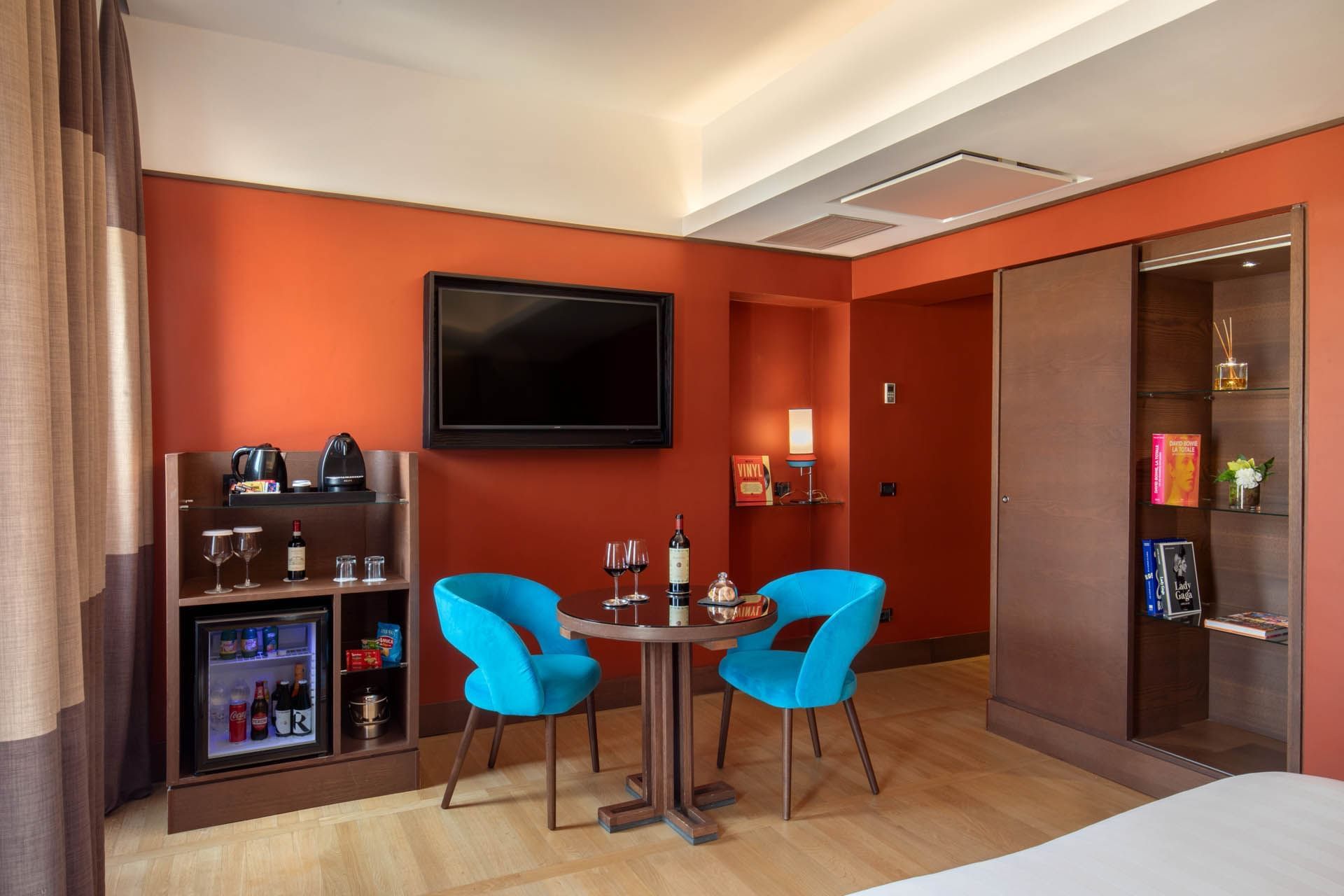 Stylish Superior Room at The Independent with a cabinet, chairs, a round table with wine glasses, and a TV
