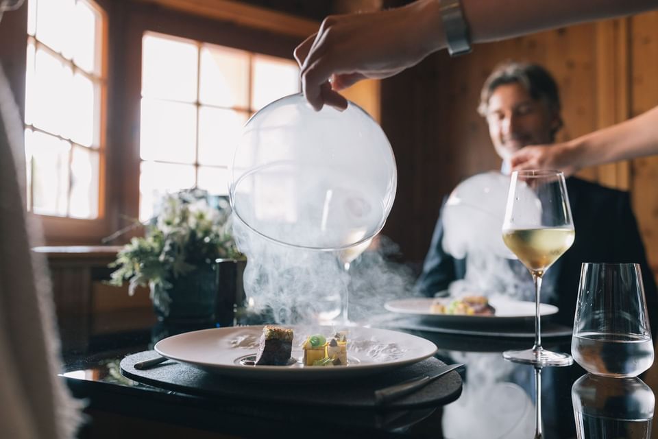 Close-up of a chef serving a dish with smoke at Liebes Rot