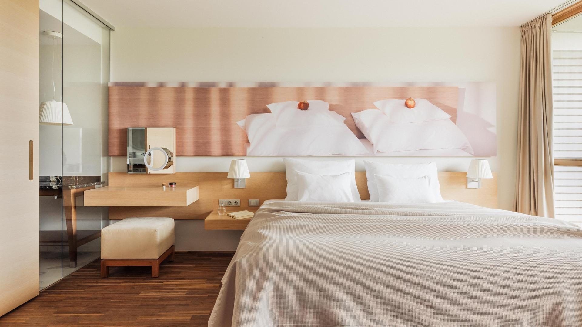 Camera da letto con due letti matrimoniali, comodini, illuminazione, specchio e bagno parzialmente visibile.