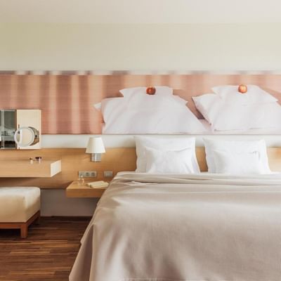 Geräumiges Schlafzimmer mit großem Bett, Nachttischen, Spiegel, Hocker und Wandkunst.
