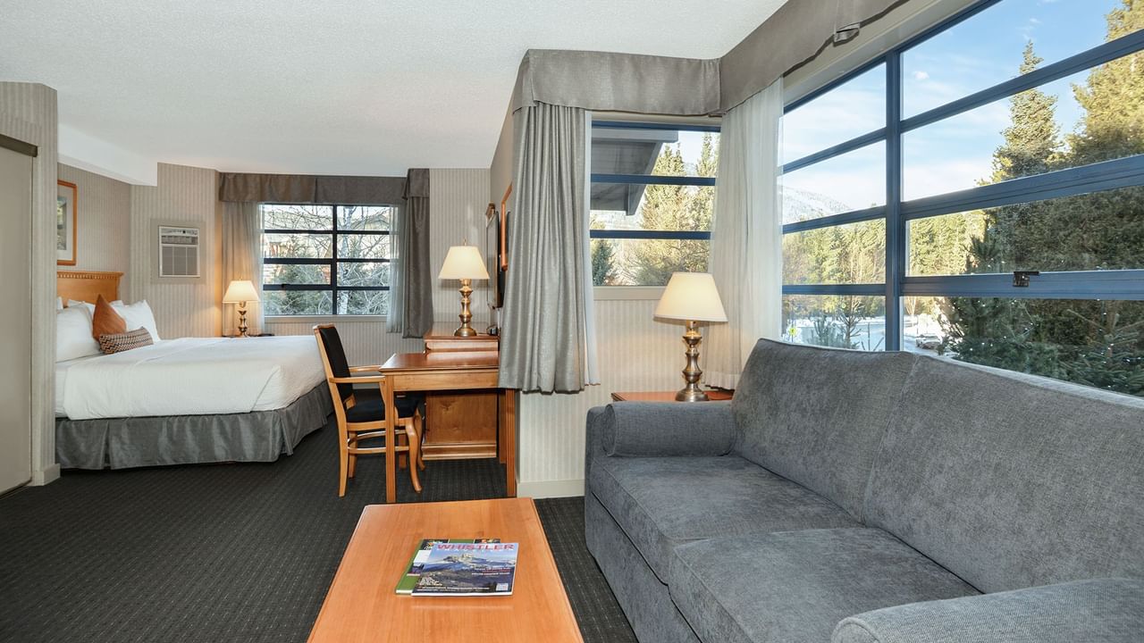 Spacious hotel suite with a king bed, elegant decor, and sofa bed.