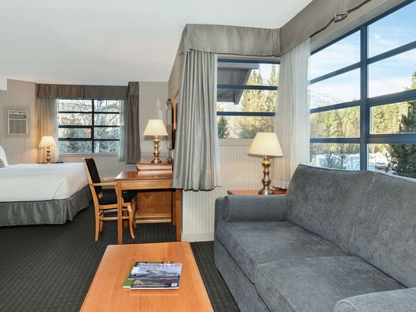 Hotel Junior Suite with king bed, sofa bed, coffee table and large windows.