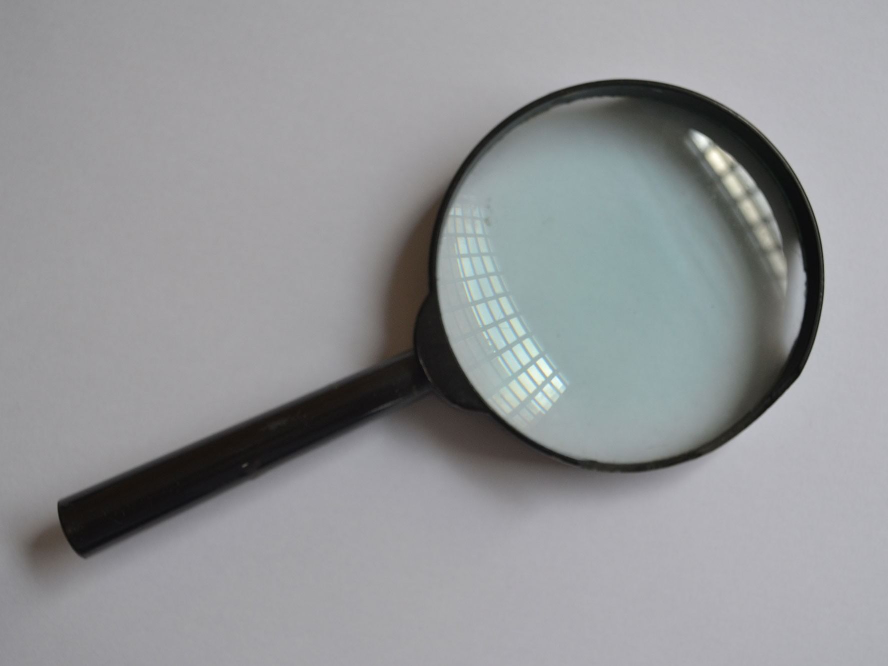 Black-handled magnifying glass on white surface.